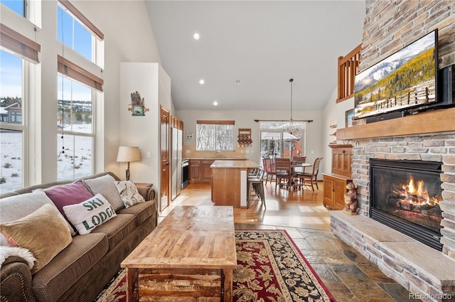 living room featuring a fireplace, high vaulted ceiling, and sink