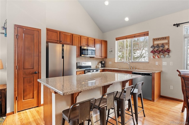 kitchen featuring appliances with stainless steel finishes, a center island, light hardwood / wood-style floors, and a kitchen breakfast bar