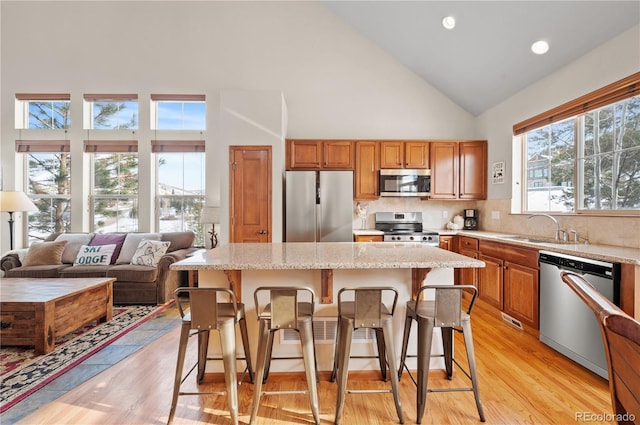 112 Deer Track Ct, Granby, CO 80446 - kitchen featuring appliances with stainless steel finishes, high vaulted ceiling, a kitchen island, light wood-style flooring, and light stone countertops