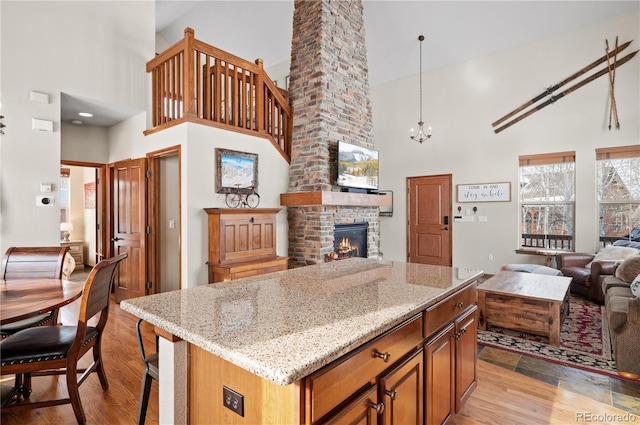 kitchen with a brick fireplace, light hardwood / wood-style flooring, high vaulted ceiling, and a kitchen island