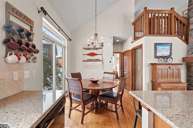 dining area with a chandelier, light wood-type flooring, vaulted ceiling, and plenty of natural light