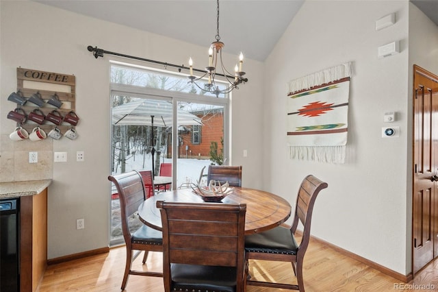 dining room with an inviting chandelier, light hardwood / wood-style floors, and vaulted ceiling