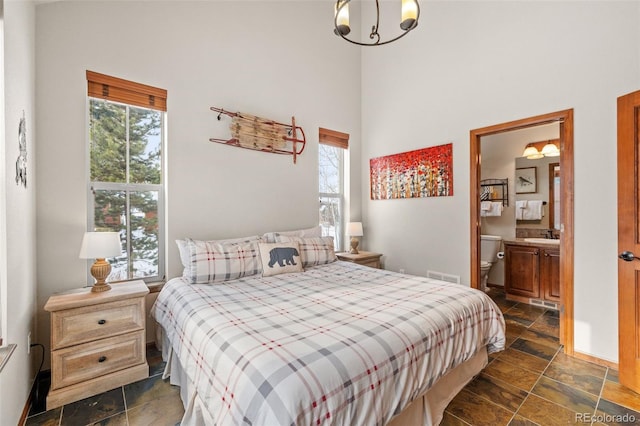 112 Deer Track Ct, Granby, CO 80446 - bedroom with stone tile floors, a towering ceiling, ensuite bathroom, and a chandelier