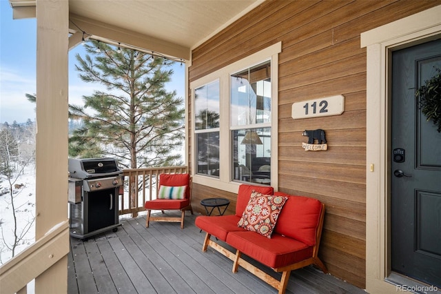 snow covered deck with area for grilling and a porch