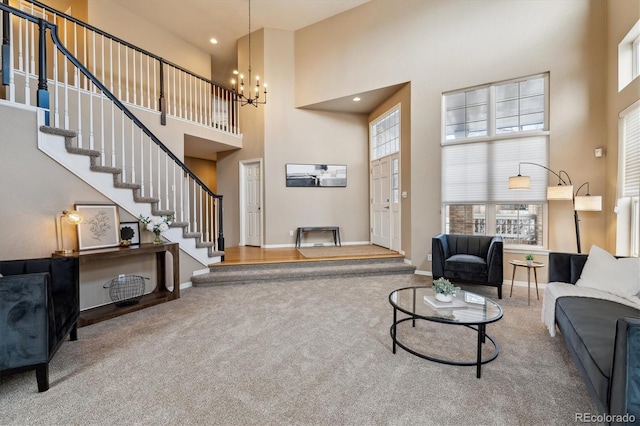 carpeted living room with stairs, baseboards, a towering ceiling, and a notable chandelier