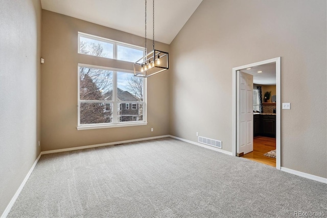 unfurnished dining area featuring baseboards, high vaulted ceiling, visible vents, and light colored carpet