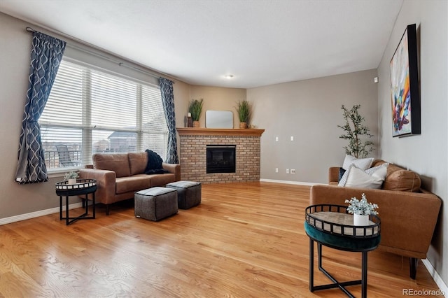 living room with a fireplace, baseboards, and wood finished floors