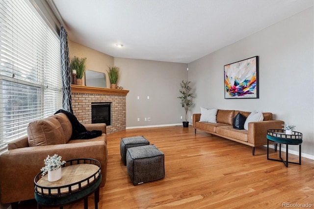 living room featuring a fireplace, baseboards, and wood finished floors