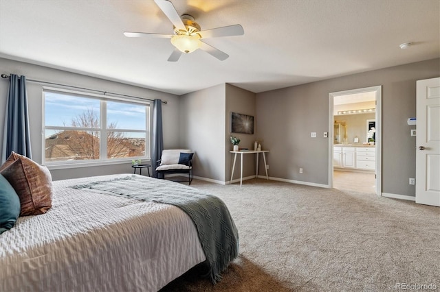 bedroom with baseboards, ensuite bathroom, a ceiling fan, and light colored carpet