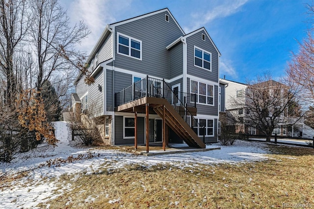 snow covered house with a deck and stairs