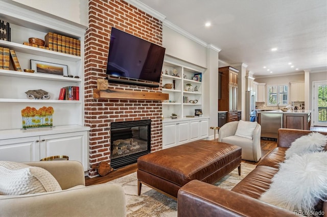 living room with a fireplace, light hardwood / wood-style floors, built in features, and crown molding