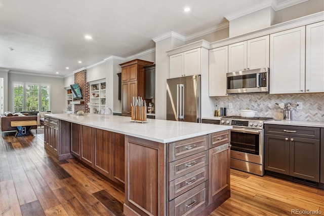 kitchen featuring hardwood / wood-style flooring, crown molding, and appliances with stainless steel finishes