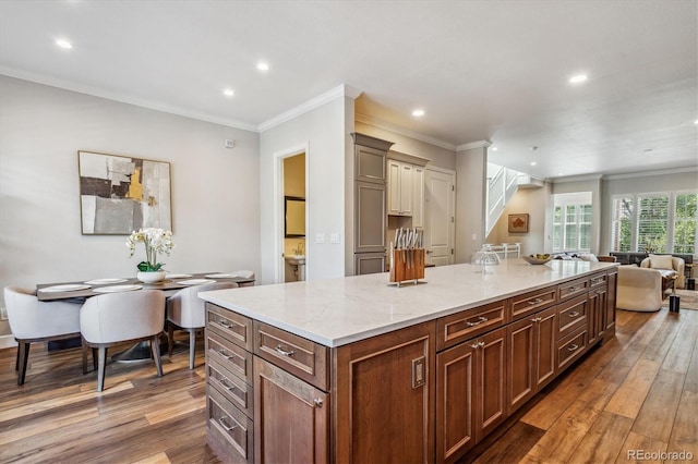 kitchen with light stone countertops, a center island, dark wood-type flooring, and ornamental molding