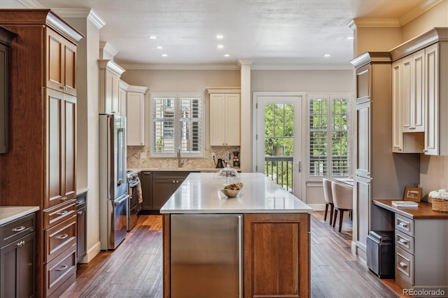 kitchen with cream cabinetry, dark hardwood / wood-style floors, a kitchen island, and appliances with stainless steel finishes