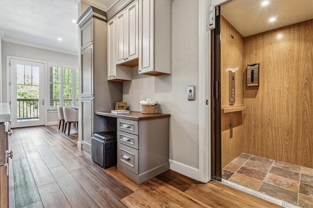 kitchen featuring elevator, hardwood / wood-style flooring, and gray cabinetry