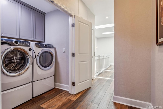 clothes washing area featuring cabinets, dark hardwood / wood-style flooring, and washing machine and clothes dryer