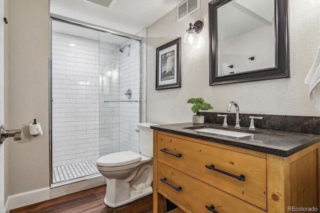 bathroom with toilet, vanity, wood-type flooring, and tiled shower