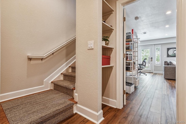 staircase with hardwood / wood-style floors and a textured ceiling