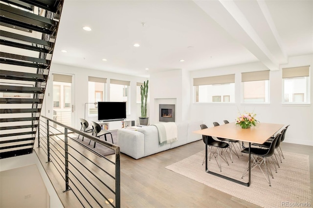 living room featuring recessed lighting, a warm lit fireplace, light wood finished floors, and a wealth of natural light
