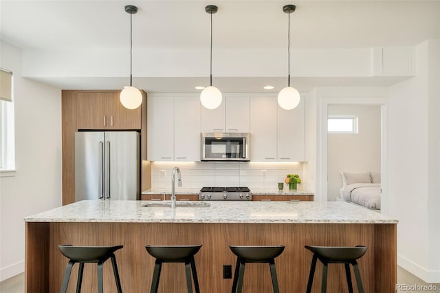 kitchen with stainless steel appliances, baseboards, a sink, and tasteful backsplash