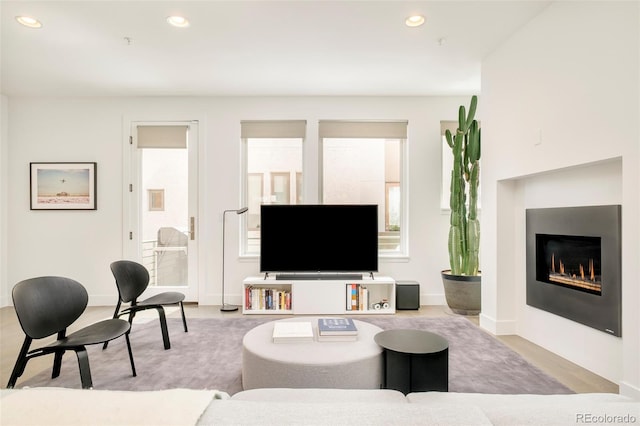 living area featuring a glass covered fireplace, baseboards, and recessed lighting