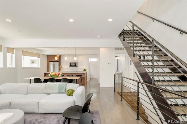 living room featuring visible vents, stairs, wood finished floors, baseboards, and recessed lighting