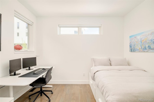 bedroom featuring baseboards, multiple windows, and light wood-type flooring