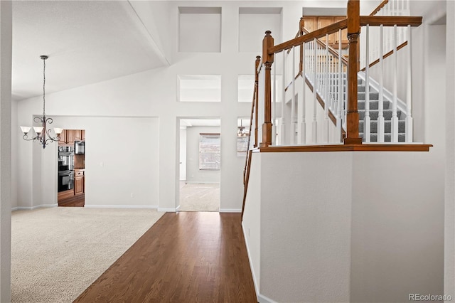 corridor with an inviting chandelier, lofted ceiling, and carpet flooring