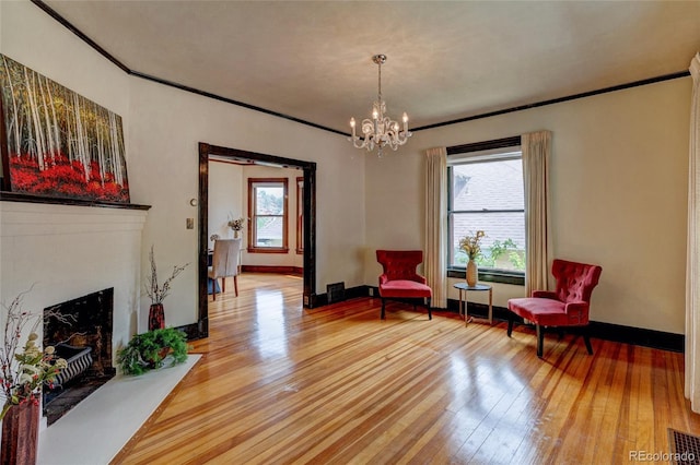 114 Cave Ave, Manitou Springs, CO 80829 - sitting room featuring wood-type flooring, a fireplace with flush hearth, baseboards, crown molding, and a chandelier
