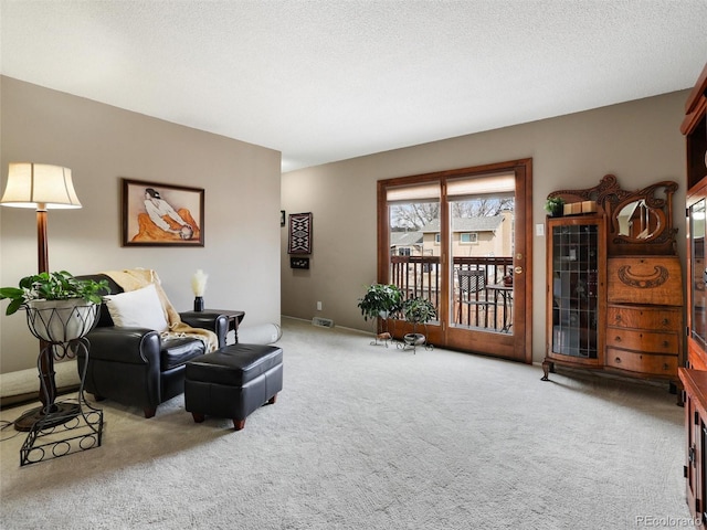 living area with carpet flooring, a textured ceiling, and visible vents