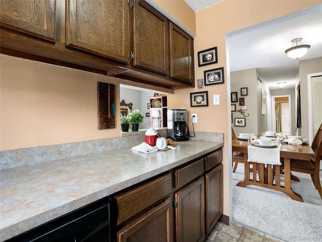 kitchen with light countertops, light carpet, and dark brown cabinetry