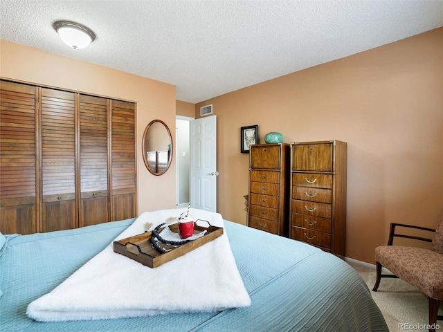 bedroom with carpet flooring, visible vents, a closet, and a textured ceiling