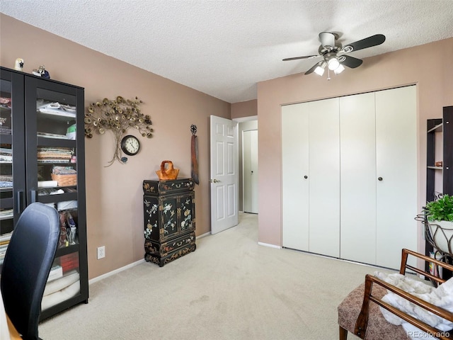 carpeted office space featuring ceiling fan, baseboards, and a textured ceiling