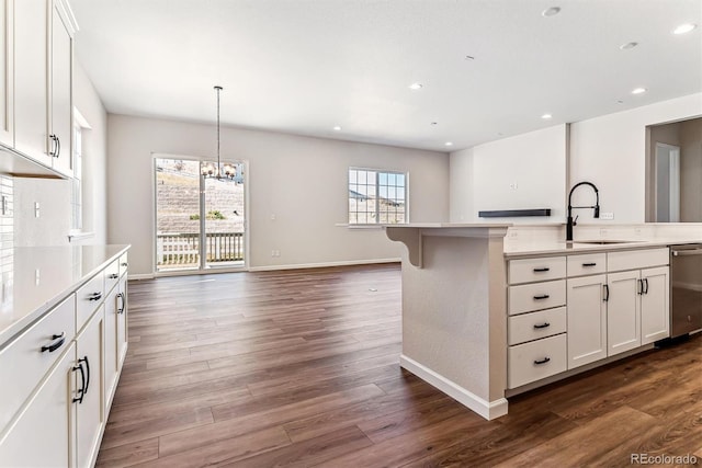 kitchen with pendant lighting, white cabinets, sink, stainless steel dishwasher, and dark hardwood / wood-style floors