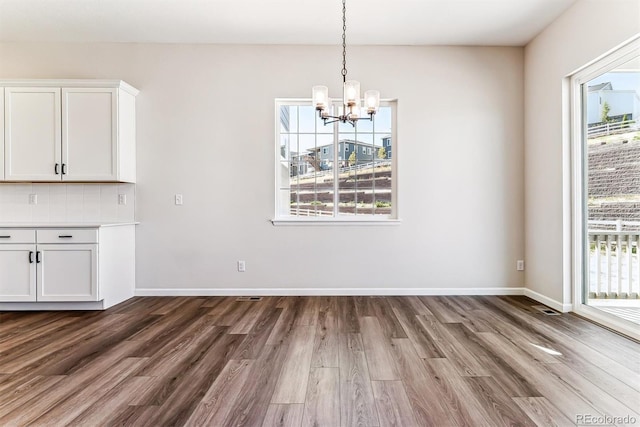 unfurnished dining area featuring dark hardwood / wood-style floors and a notable chandelier