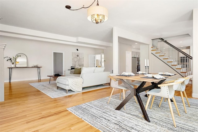 dining space featuring a notable chandelier, light wood-style flooring, recessed lighting, baseboards, and stairs