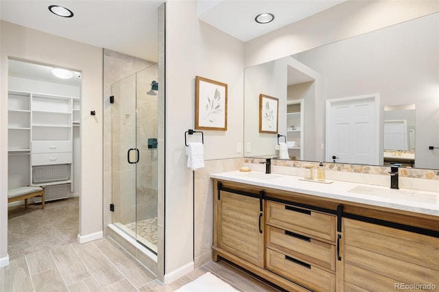 bathroom with a walk in closet, a stall shower, and vanity