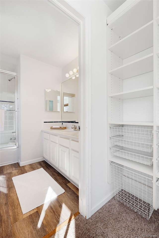 bathroom with a sink, wood finished floors, baseboards, and double vanity