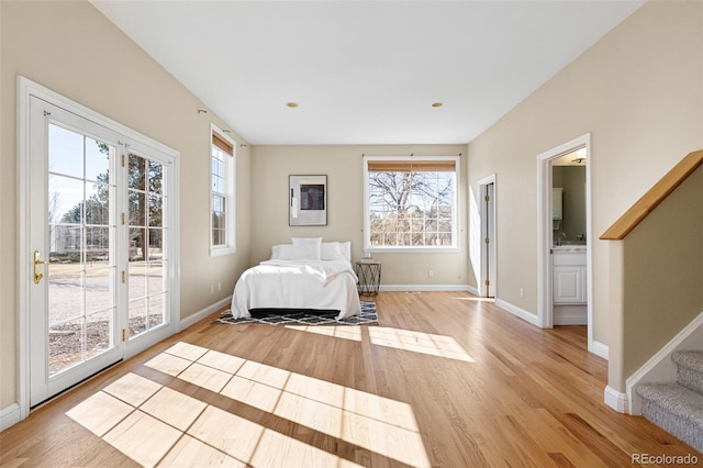 bedroom with access to exterior, light wood-style flooring, multiple windows, and baseboards