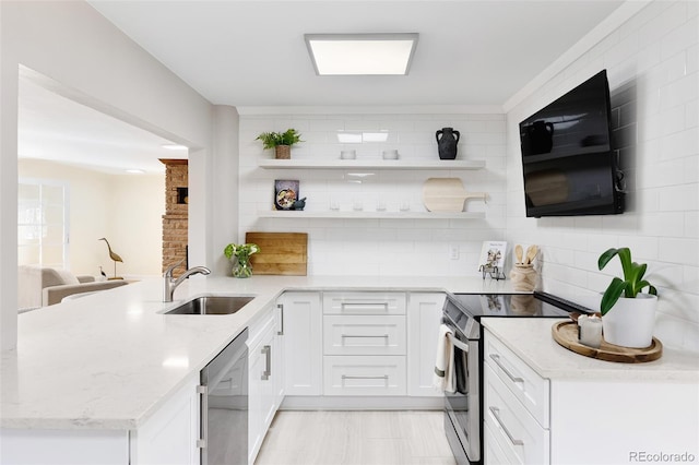 kitchen with open shelves, a peninsula, a sink, stainless steel appliances, and tasteful backsplash