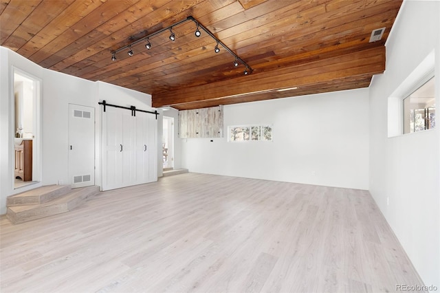 interior space with plenty of natural light, wooden ceiling, a barn door, and wood finished floors