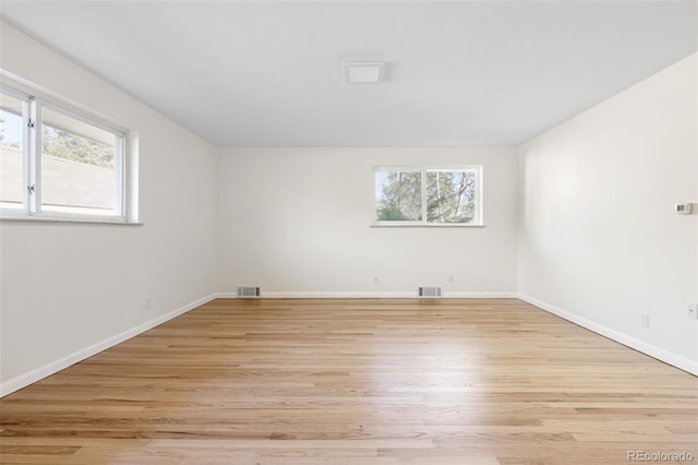 unfurnished room featuring light wood-style flooring, a healthy amount of sunlight, and visible vents