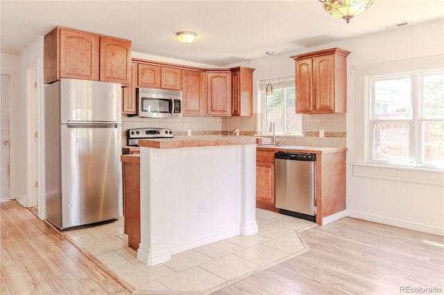 4368 Benton St, Denver, CO 80212 - kitchen featuring stainless steel appliances, light countertops, backsplash, hanging light fixtures, and light wood-style floors
