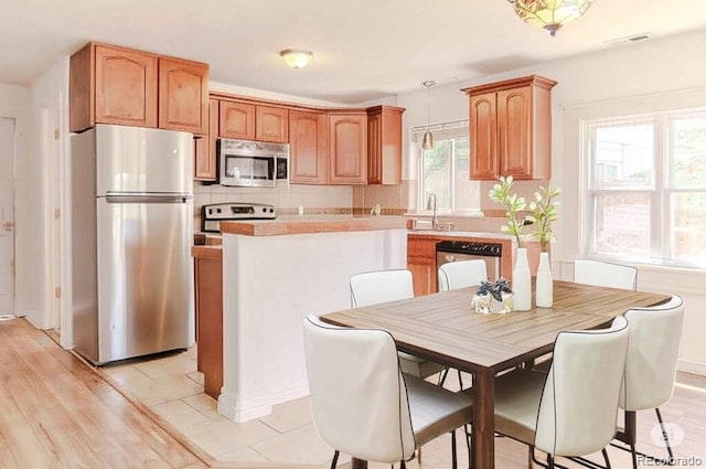 4368 Benton St, Denver, CO 80212 - kitchen featuring stainless steel appliances, decorative backsplash, pendant lighting, light countertops, and a center island