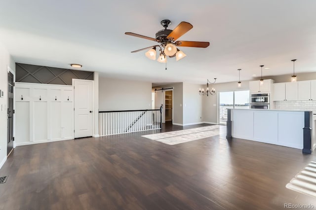 31142 County Road 18, Keenesburg, CO 80643 - kitchen featuring ceiling fan with notable chandelier, a barn door, baseboards, and dark wood finished floors