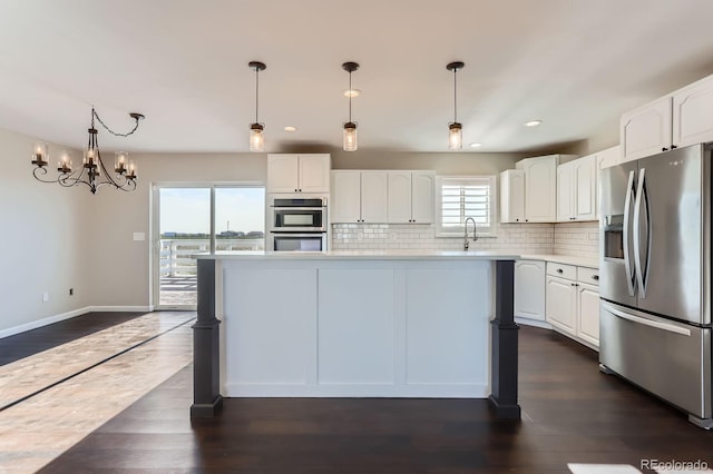 31142 County Road 18, Keenesburg, CO 80643 - kitchen with stainless steel appliances, white cabinetry, backsplash, light countertops, and a kitchen island