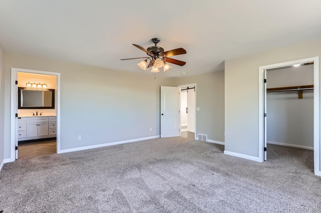 31142 County Road 18, Keenesburg, CO 80643 - unfurnished bedroom with a sink, carpet floors, visible vents, a barn door, and a spacious closet