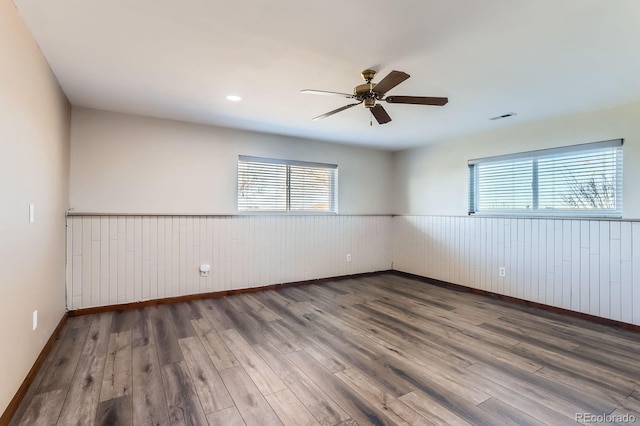 31142 County Road 18, Keenesburg, CO 80643 - spare room featuring a ceiling fan, wainscoting, visible vents, wooden walls, and wood finished floors