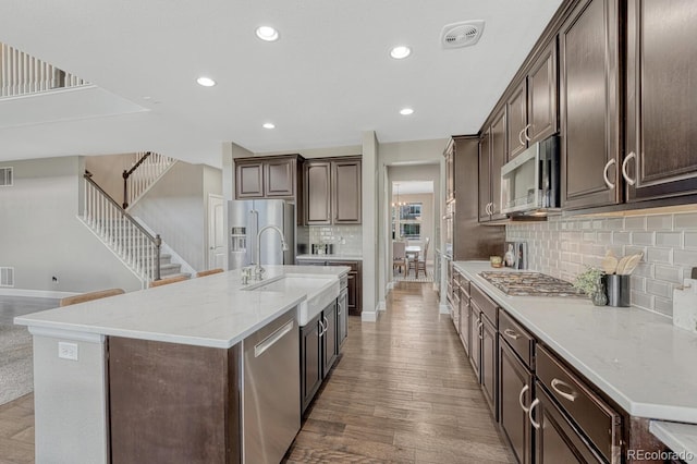 6738 Esmeralda Dr, Castle Rock, CO 80108 - kitchen featuring stainless steel appliances, a sink, tasteful backsplash, dark brown cabinetry, and a center island with sink