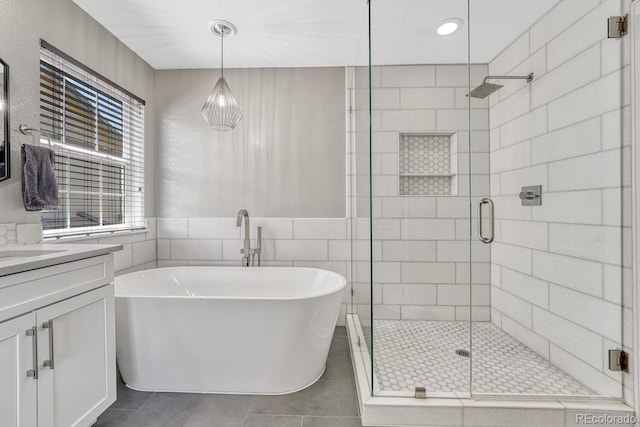 6738 Esmeralda Dr, Castle Rock, CO 80108 - bathroom with a freestanding bath, vanity, a stall shower, tile patterned floors, and tile walls